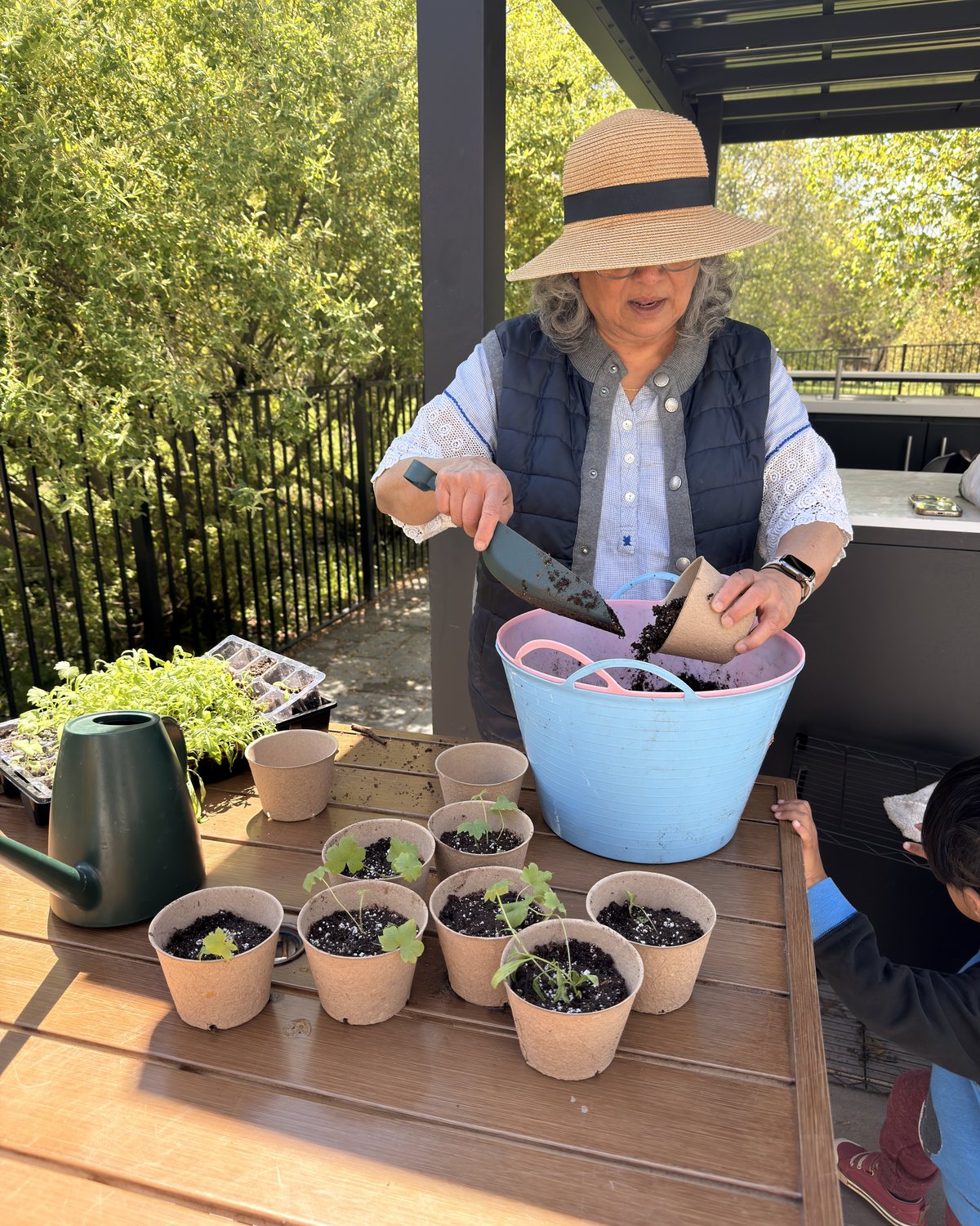 Geeta potting seedlings on a patio table.